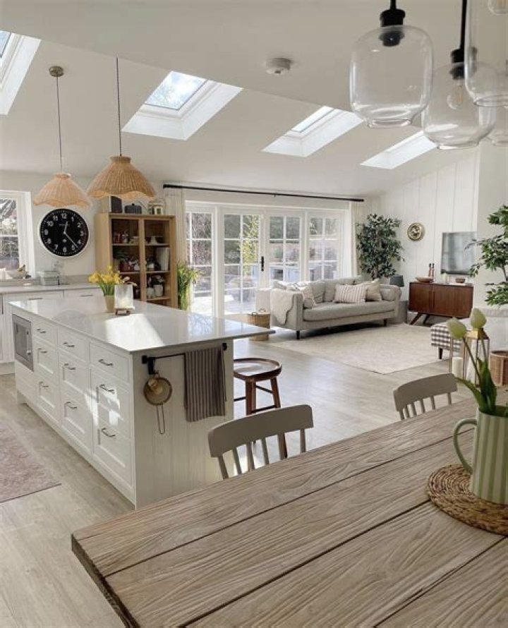 Minimalist staged kitchen dining living room in open concept home with large windows.